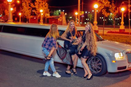 night portrait of a group of girls on a background of a white limousine. they are having fun. night life. limousine party