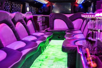 The interior of a luxury limousine illuminated in purple and green. Vehicle for party, wedding.